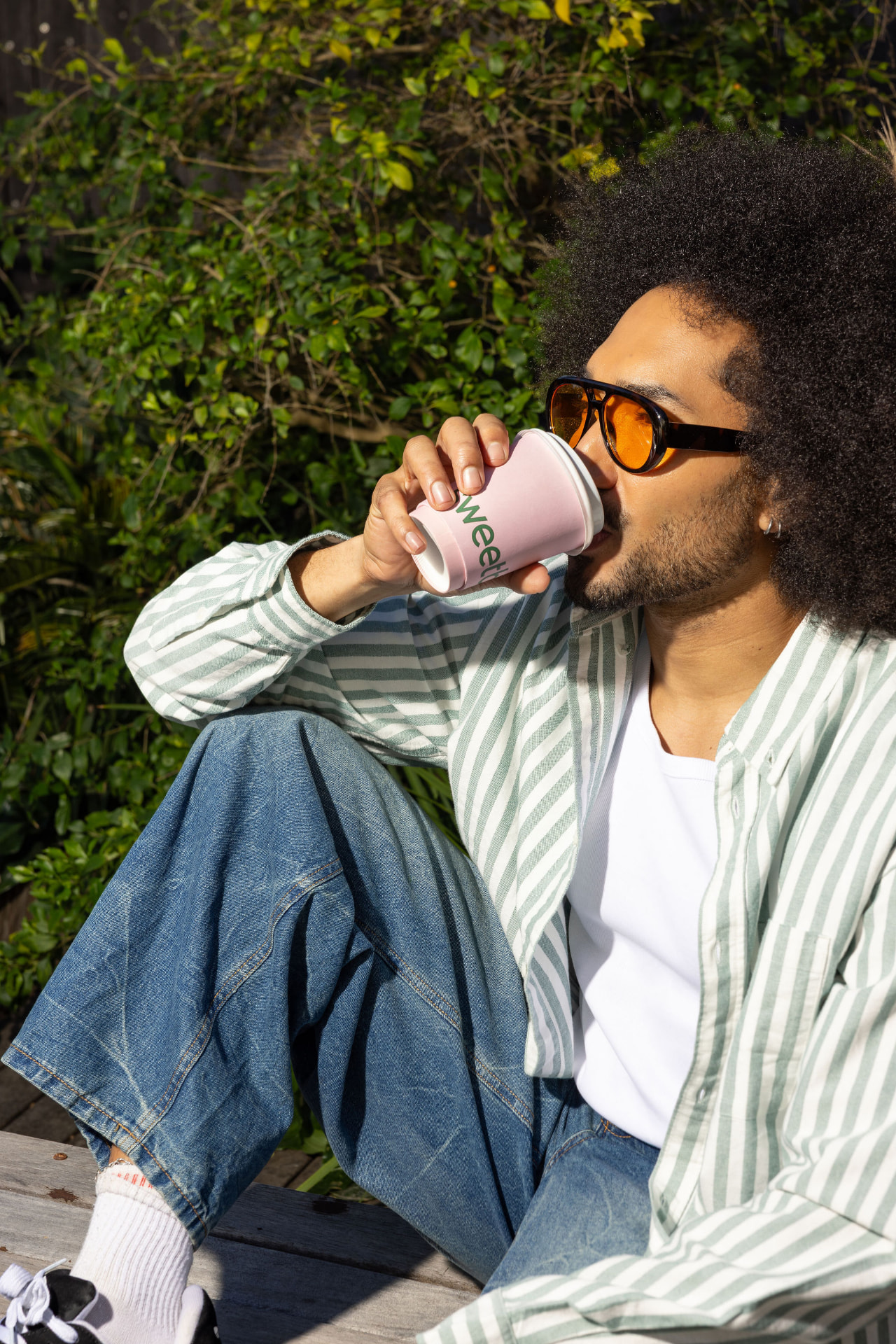 A customer relaxing outside with a pink Sweetbeet coffee cup